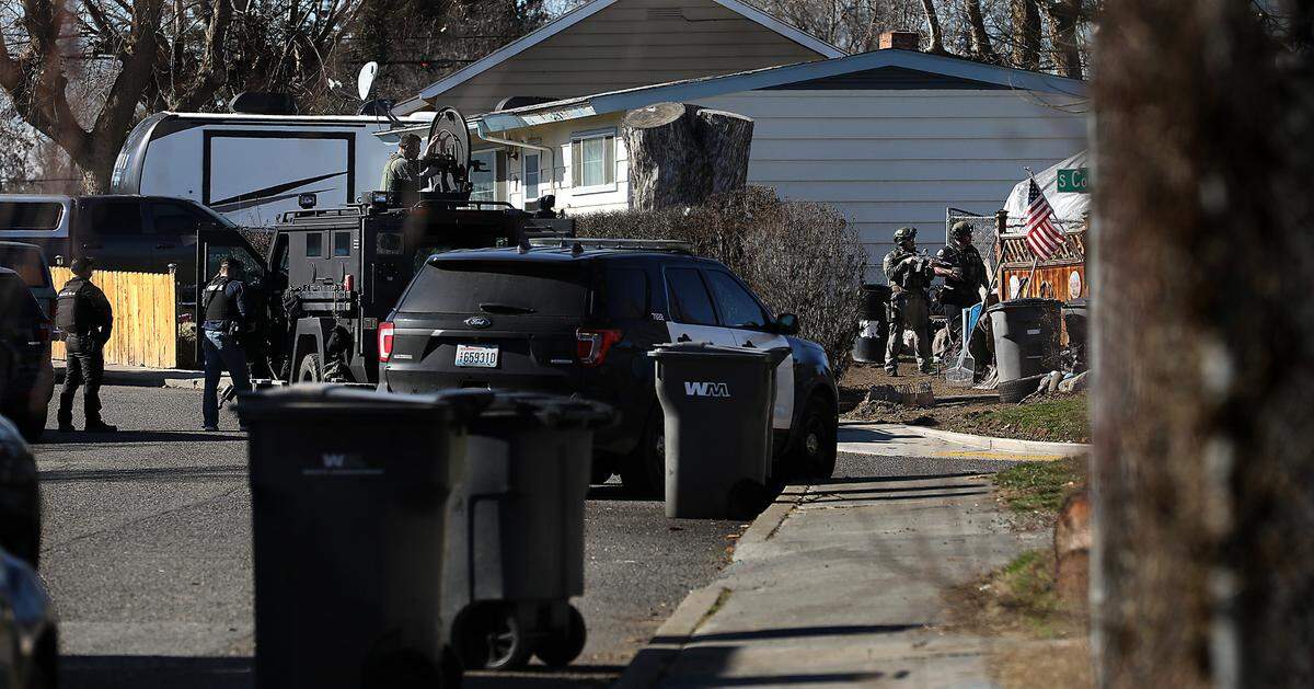 Members of the Tri-City Regional SWAT team surround a home at the intersection of West 6th Place and South Conway Street on Thursday in Kennewick. A wanted suspect was barricaded the home and police were working to get the person to come out, according to a social media post from the department. The standoff is in a neighborhood south of Westgate Elementary School.