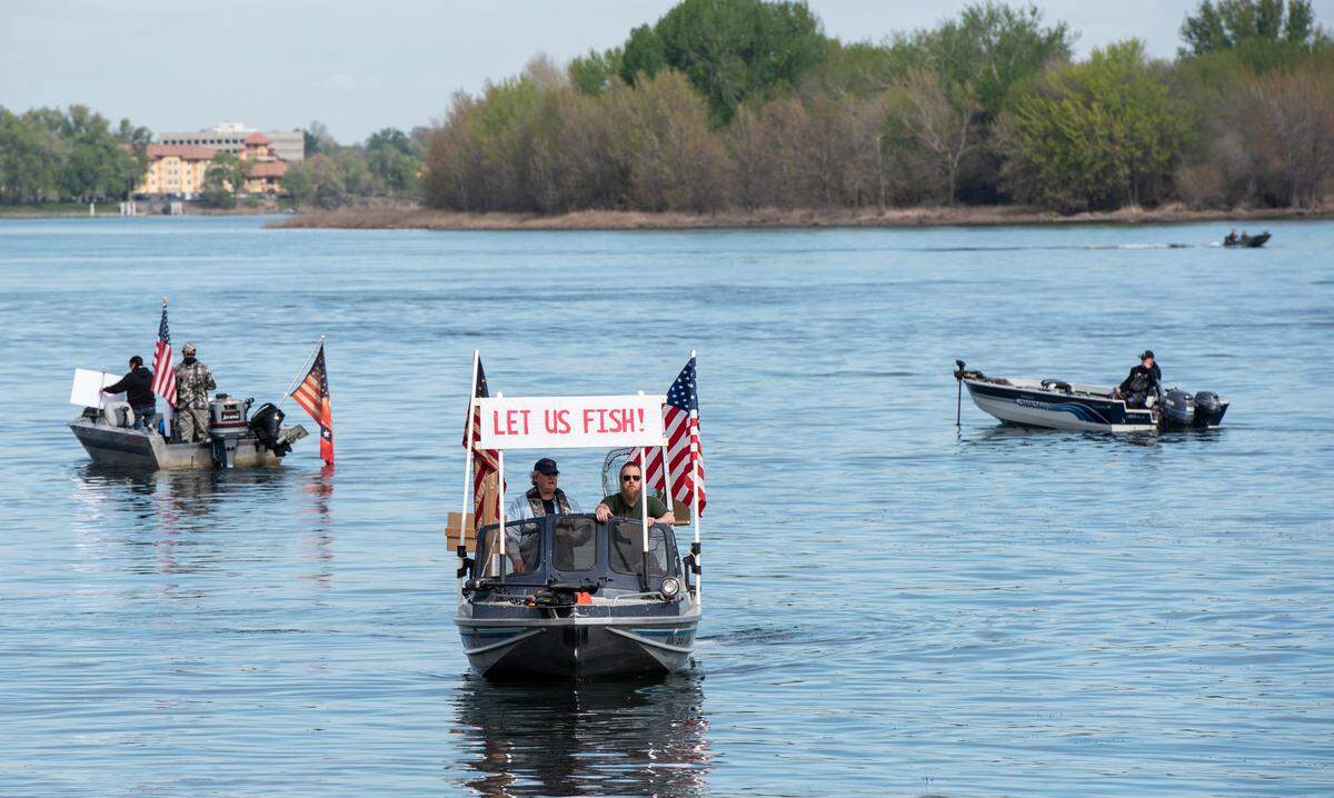 Boaters motor around Columbia Point Park Marina in Richland on Saturday with signs that read “Let Us Fish!” to demonstrate against a measure set by the Washington Department of Fish and Wildlife that prohibits recreational fishing during the coronavirus outbreak.