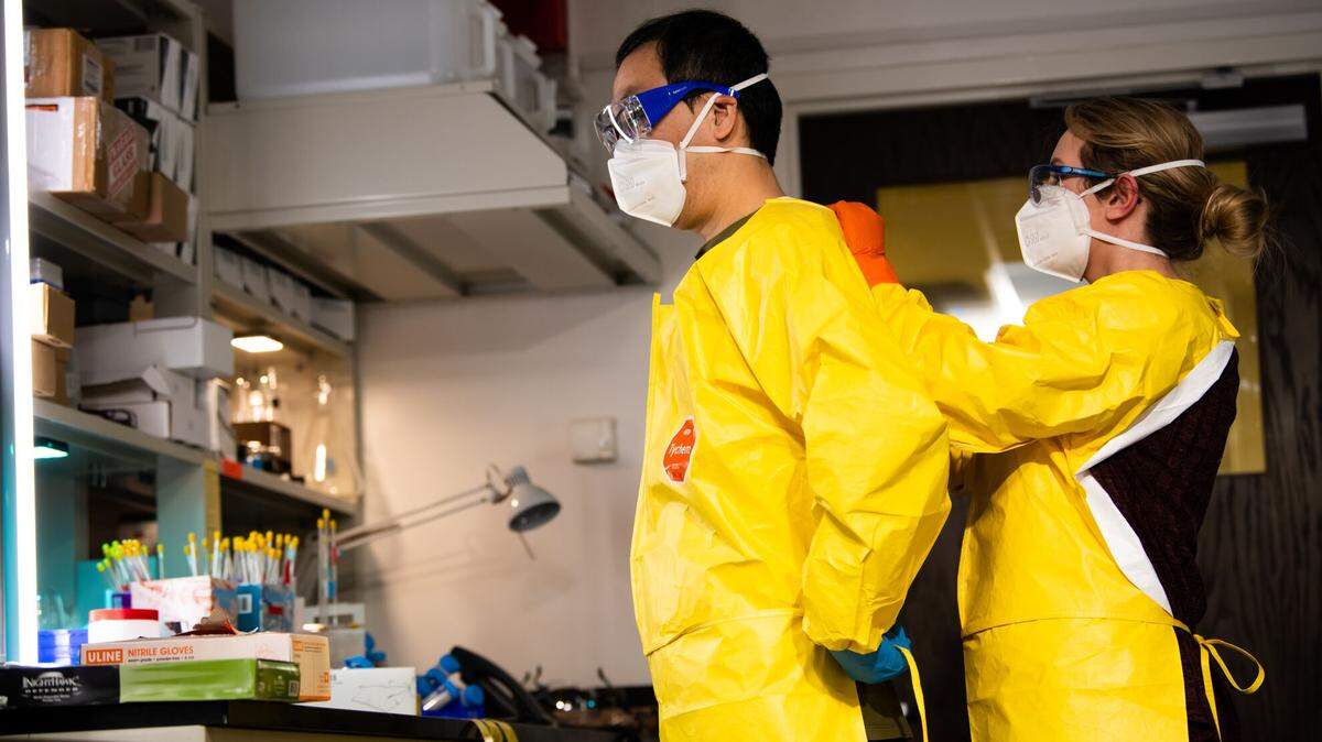 Scientists Kai-For Mo and Ashley Bradley help each other into personal protective equipment before working in the fentanyl laboratory at Pacific Northwest National Laboratory.
