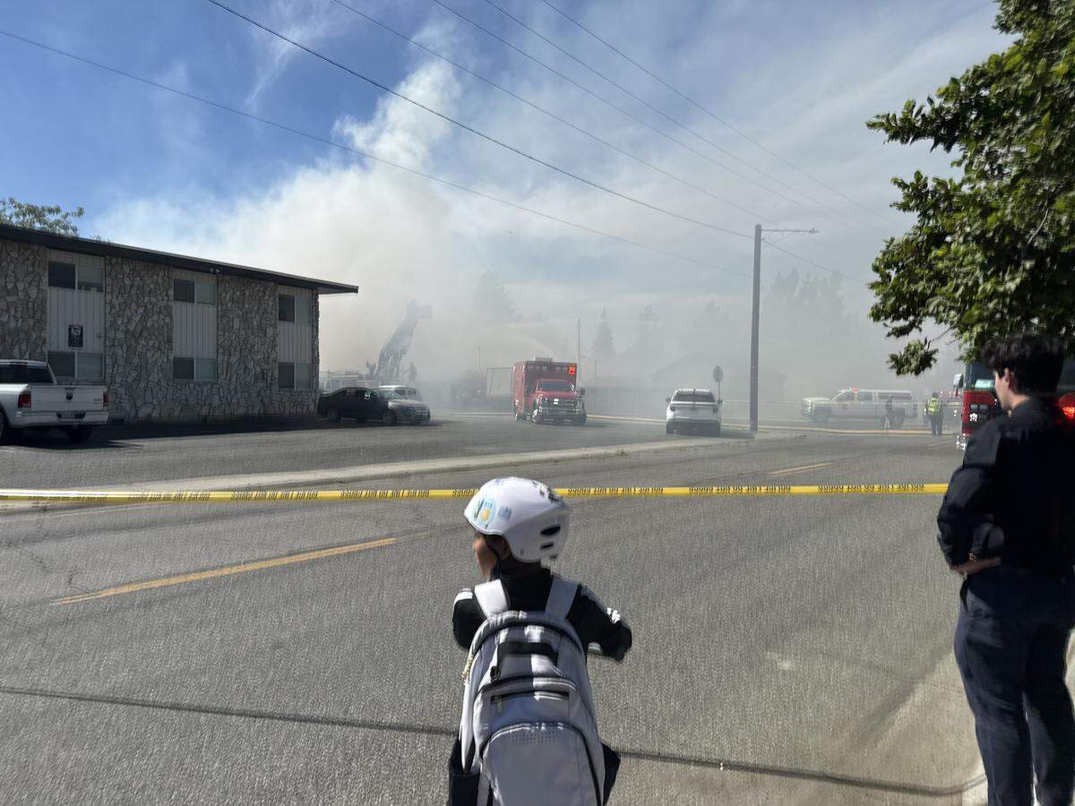 A child watches as smoke billows from a two-alarm blaze at a notorious Richland “junkyard” house.