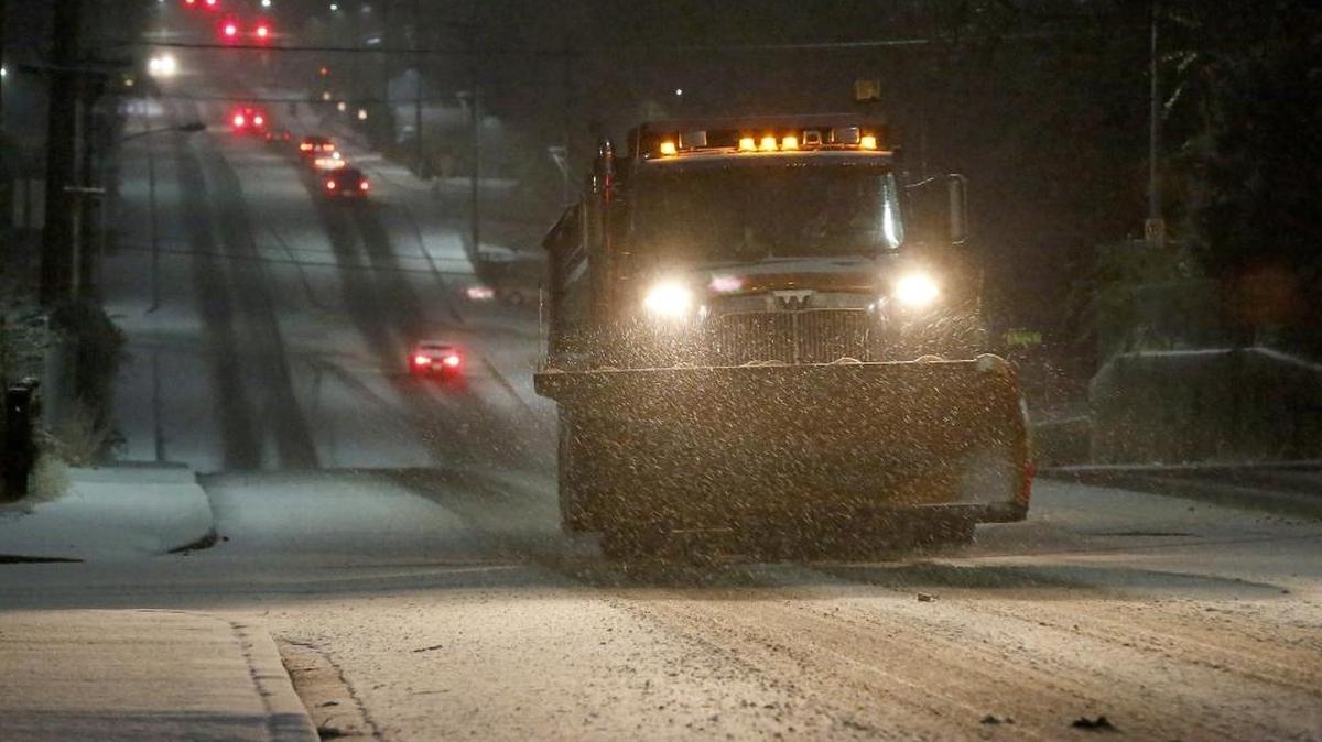 A city snow plow drives up the hill on South Vancouver Street near West 10th Avenue in Kennewick early Tuesday morning while snow from the area's first winter storm continues falling and coating the roadways. Numerous closures and delays are being reported by schools and at some area work sites because of hazardous driving conditions.