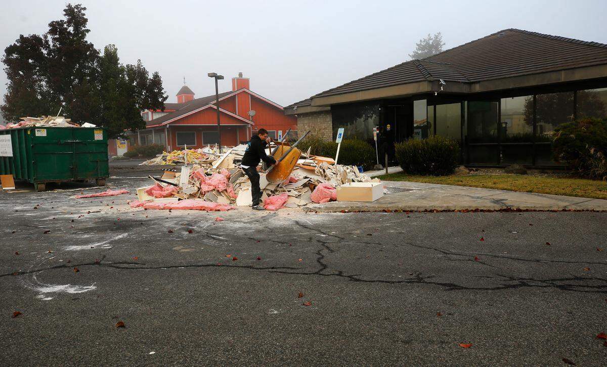 A worker hauls out interior demolition debris from a building that formerly housed a clinic at 3000 W. Kenewick Ave.