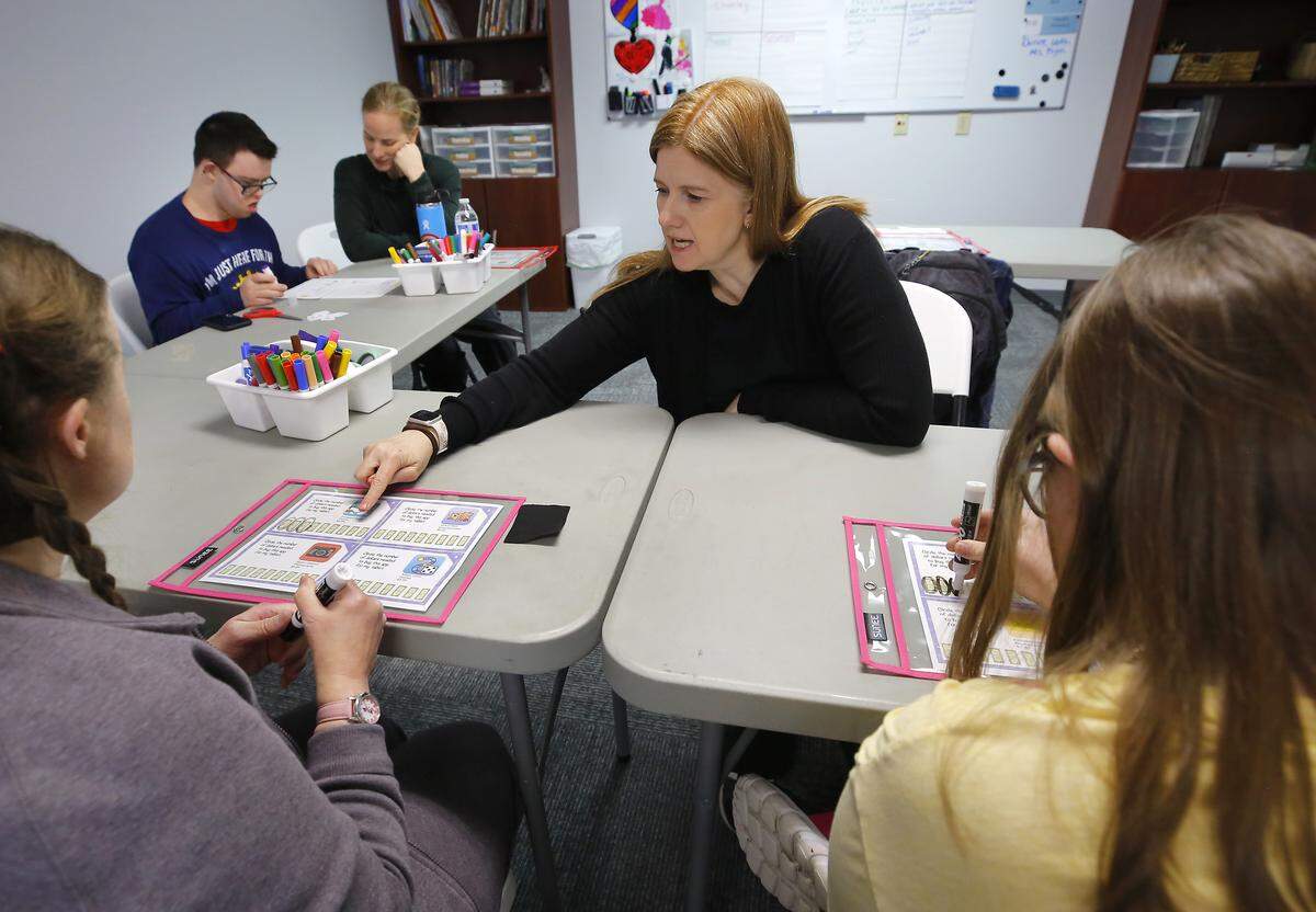 Julie Sumsion, founder and head teacher at Beautiful Day Learning, works with student Melissa Sprague on a math question during a recent classroom exercise at the new Kennewick facility. Teacher Ashley Stratton helps student Brady Cleveringa at left while Sumsion's daughter, Aidan, sits next to Sprague, at right.
