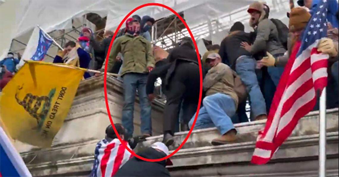 Matthew Klein, in green jacket and holding flag at left, appears on the wall within the restricted area of the Capitol grounds in Washington D.C. at 2:11 p.m. on Jan. 6, 2021, according to FBI officials.