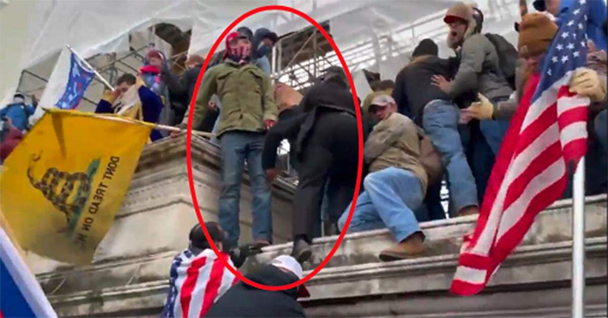 Matthew Klein, in green jacket and holding flag at left, appears on the wall within the restricted area of the Capitol grounds in Washington, D.C., at 2:11 p.m. Jan. 6, says the FBI.