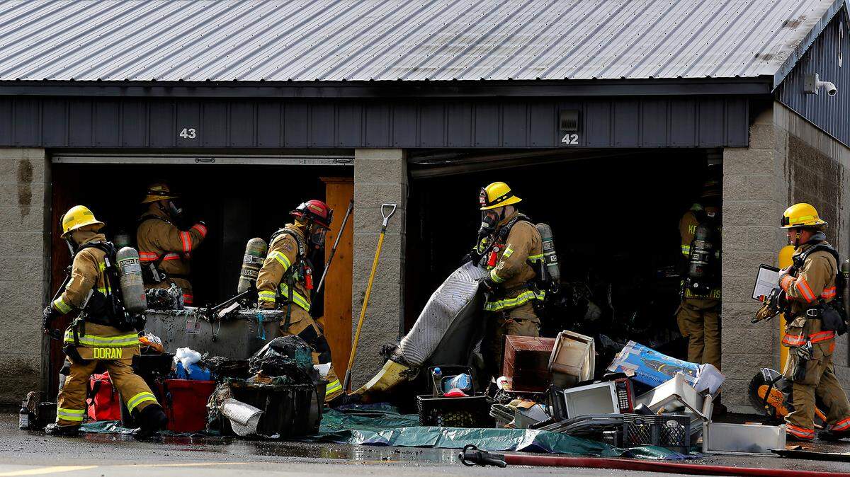 Firefighters empty the burned contents from a storage unit Wednesday afternoon at the Southridge Storage business in Kennewick.
