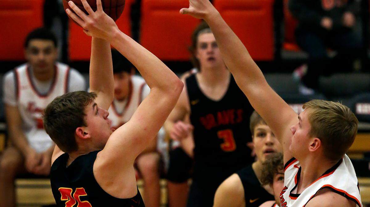 Kamiakin’s Tyler Bilodeau (35) gets his shot off under heavy pressure from Kennewick defender Nathan Knapik during their Jan. 18, 2022 game at Kennewick High School.