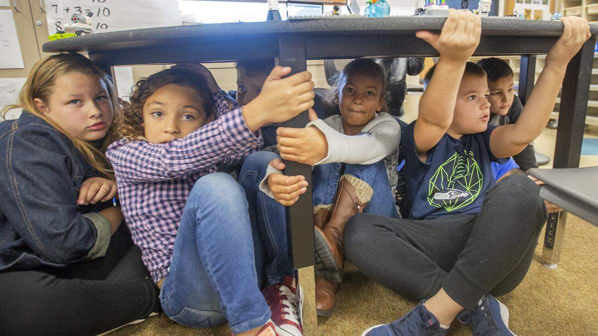 Third-graders in Maya Donnelly’s class take cover under their desk during Thursday’s Great Washington Shakeout at 10:18 a.m. at Barbara McClintock STEM Elementary School. The shakeout happens statewide every year on Oct. 18 at 10:18 a.m., when schools practice how to be safer in case of an earthquake.