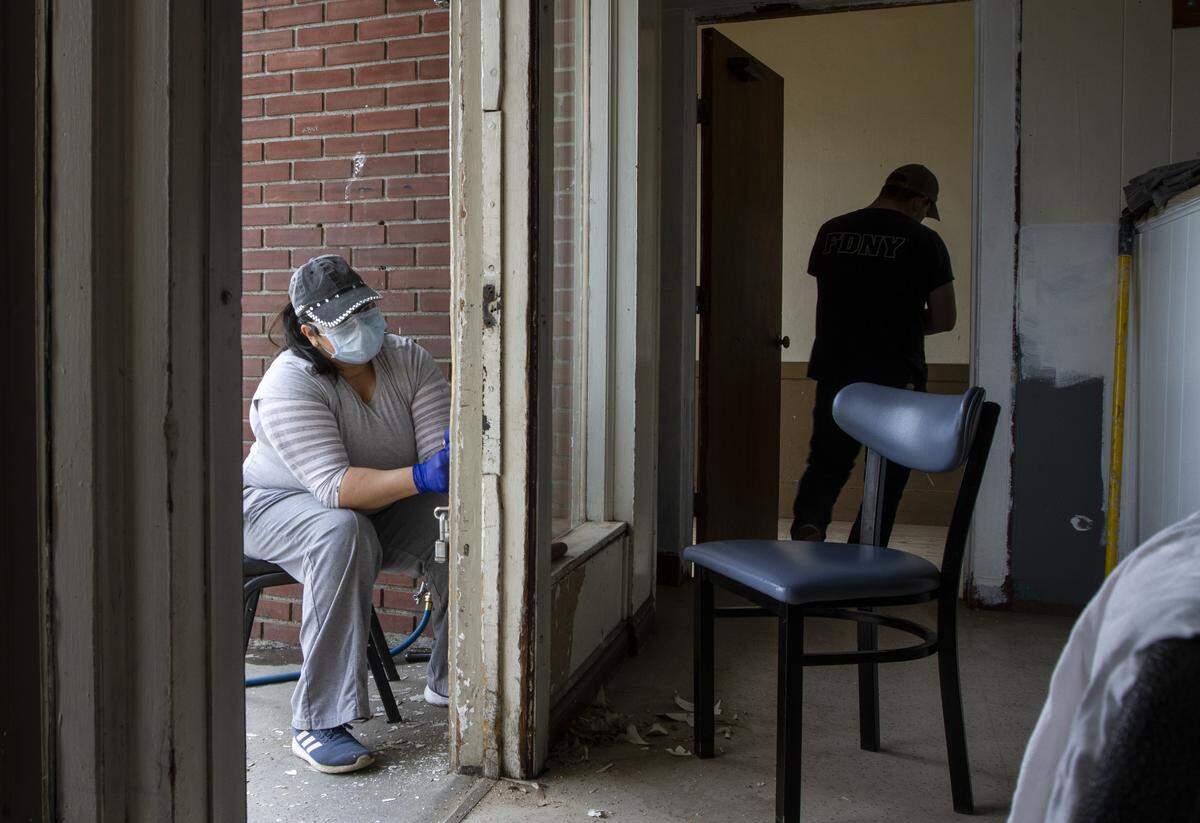 Employees from The Lodge at Columbia Point scrape paint at the entrance to Grace Kitchen, a Pasco nonprofit.