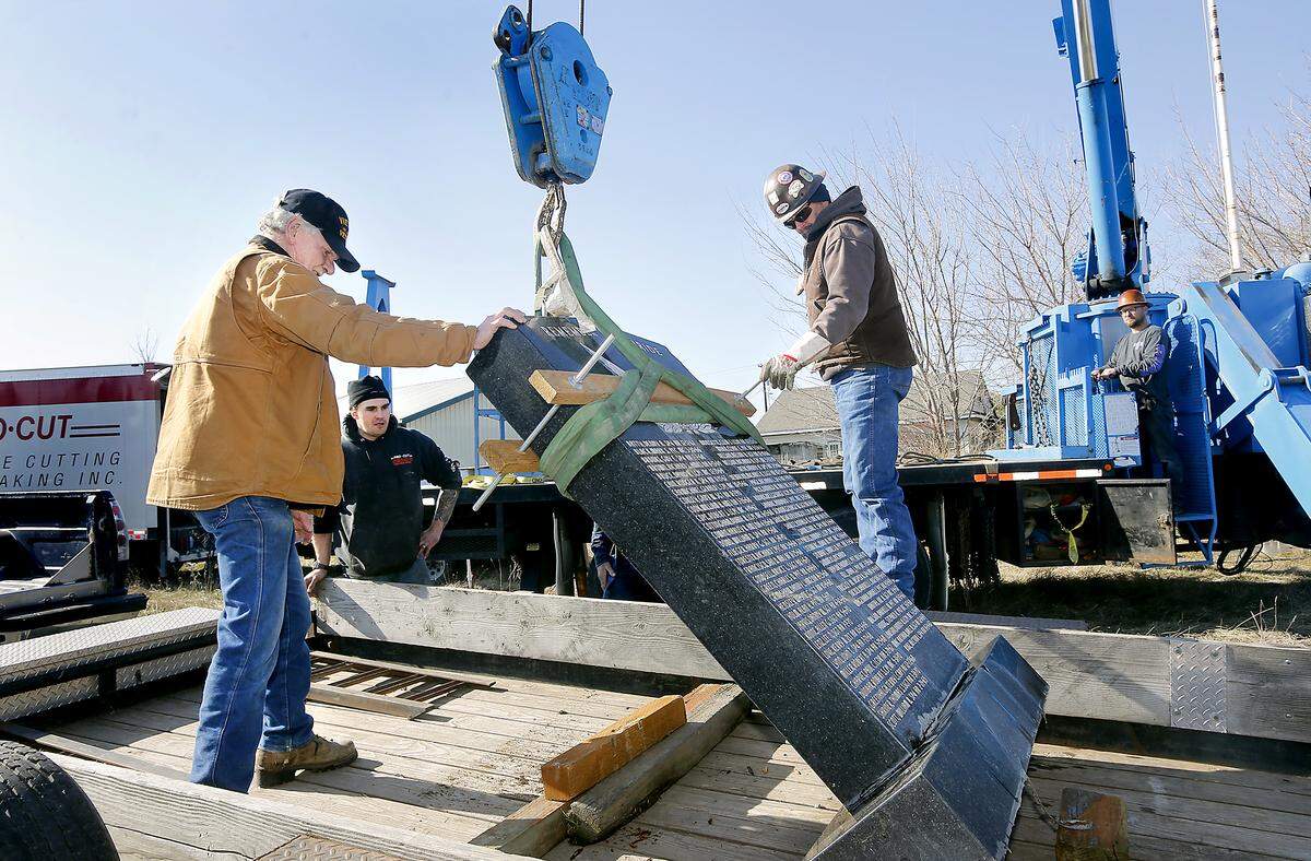 Vietnam veteran Bobby Dale Albers, left, helps guide an engraved memorial marker onto a trailer after it was lifted from the ground behind his former Finley home. He was helped by Britt Samsel of Pro-Cut Concrete Cutting and Breaking, and Lampson International employees Rick O’Hair, middle, and Chad Soland, right. Watch a video at: tricityherald.com/videos