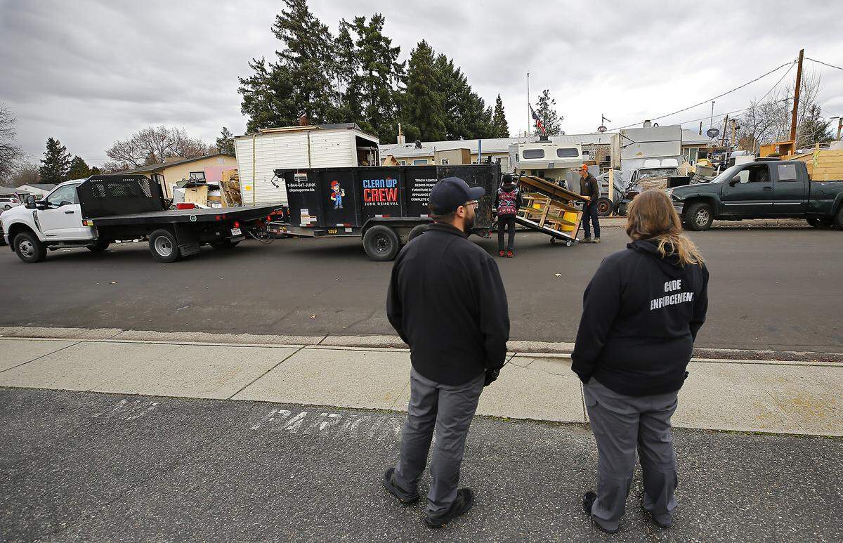 Nick Mutrux, Richland code enforcement supervisor, and code enforcement officer Stephanie Dorko, right, watch as a contractor hired by the city begins removing junk.