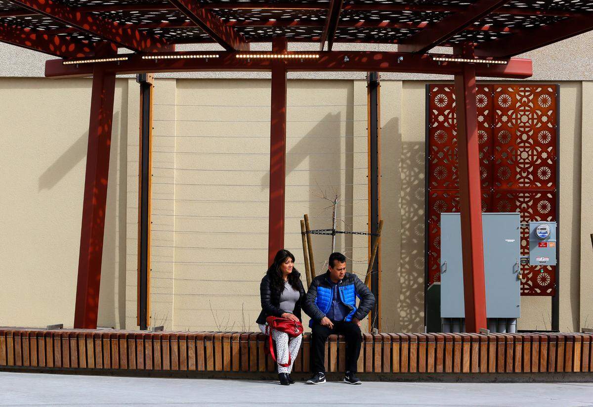 Perla Hernandez, left, and Samuel Becerra use the new seating in the newly renovated Peanuts Park while waiting for Friday’s ribbon cutting ceremony to begin at the outdoor facility in downtown Pasco.