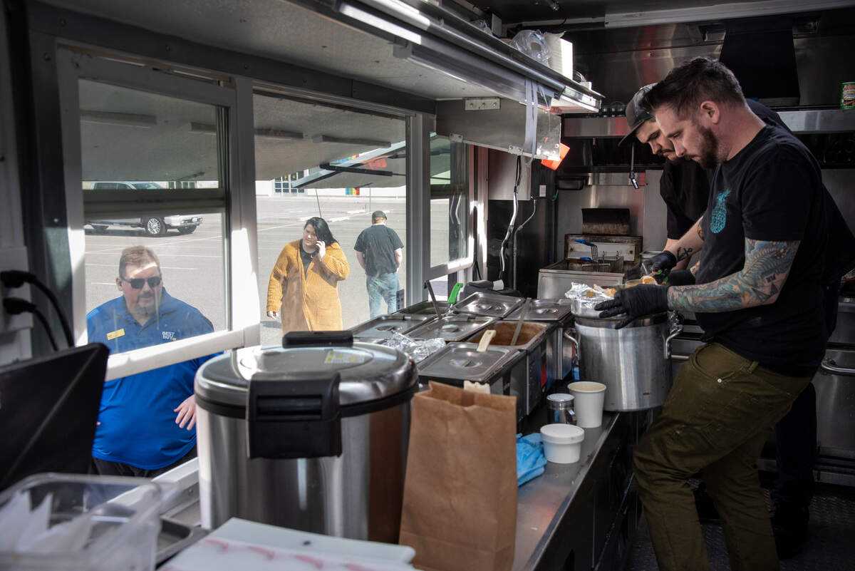 Anthony Federico, 41, far right, and Matt Miller, 29, right, prepare food for a line of patrons outside of the Bayou Some Cajun food truck in the parking lot of Columbia Center mall.