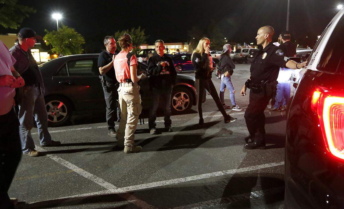 Sgt. Dave Blosser of the Kennewick Police Department talks with members of Defend The Tri stationed one night in the retail mall on West Canal Drive recently damaged by vandals and looters. The group’s organizer says they’ve been in contact with officials at the Kennewick and Pasco police departments.