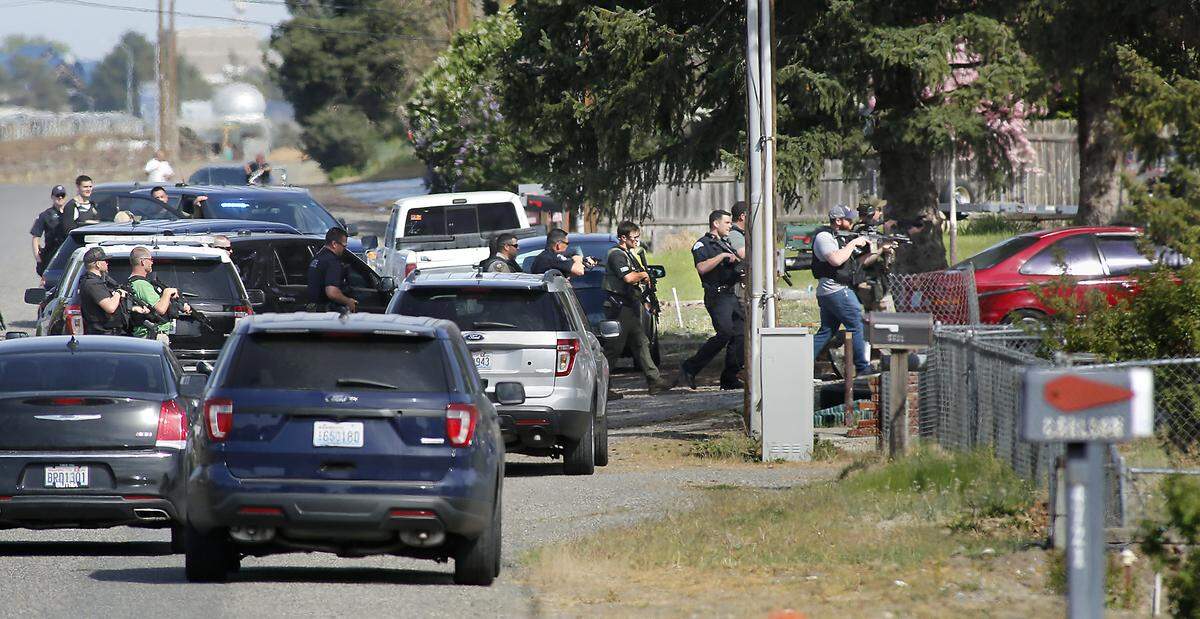 Law enforcement officers from various agencies cautiously approach a house on Livingston Road near Road 48 in Pasco where they arrested murder suspect Jonah Glass for Friday’s murder in a Richland motel room.