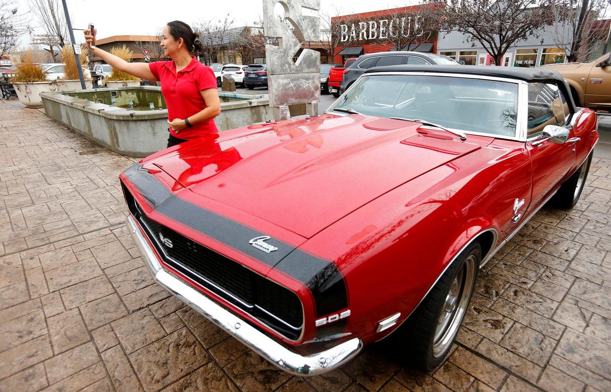 Leticia Whitten, owner of Miss Tamales in Richland, uses her cellphone Tuesday for a selfie with the 1968 Camaro convertible called FLVRTWN featured in the Dines, Drive-Ins & Dives show hosted by chef Guy Fieri. The popular TV personality was in town to record interviews at some local restaurants. Watch a video at: tricityherald.com/video