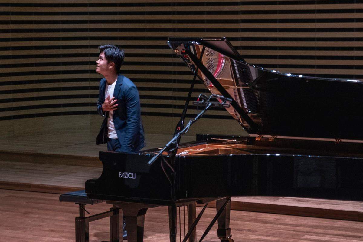 Jim-Isaac Chua bows next to a piano for a performance. The world-renowned pianist currently lives in Poland, but lived in Richland as a child.