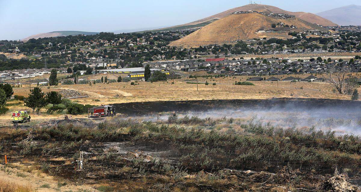 Firefighters monitor a smoldering five acre brush fire Wednesday morning on Thompson Hill near the corner of Columbia Center Boulevard and 21st Avenue in Kennewick. It’s one of five fires that started after 11 p.m.