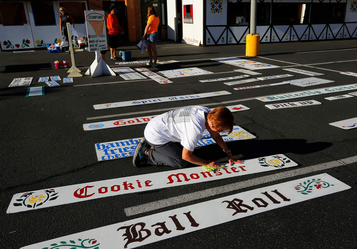 Volunteer Joan Rosenberg scrubs clean signs used on the various booths set up for the 47th annual Sausage Fest at the Christ the King Catholic School in Richland.&nbsp;