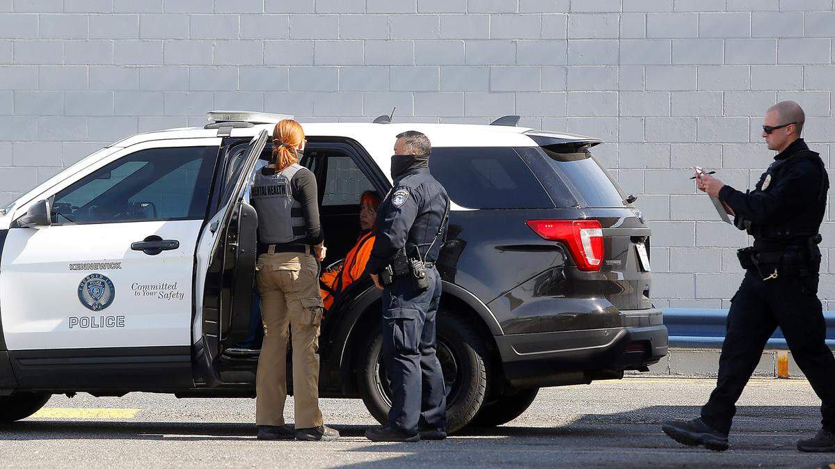 A Kennewick police officer and a mental health professional talk to a woman in the back of patrol car after she was arrested Wednesday in line at the Zip’s restaurant drive-thru window.