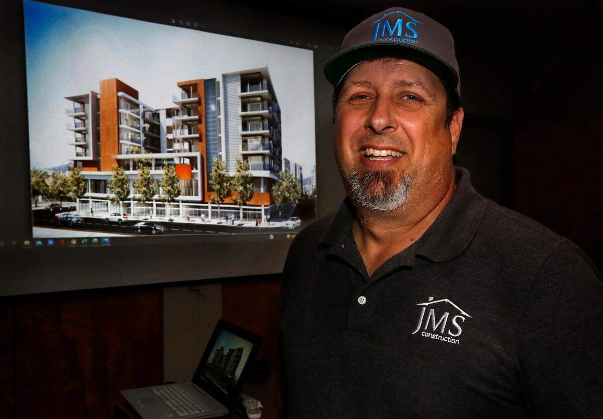 James Sexton, owner of JMS Construction, stands in fron of a projected artist rendering of an eight story 55+ rental community building that will be part of the Osprey Pointe development his company is working towards starting on in Pasco.