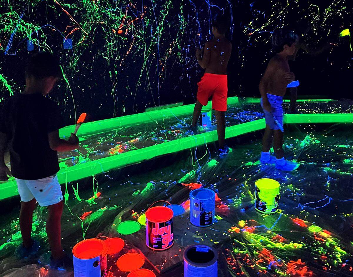 Brittney Hallman, her sons and their friends spray paint in the splatter tunnel in Let’s Glow Mini Golf in Kennewick.