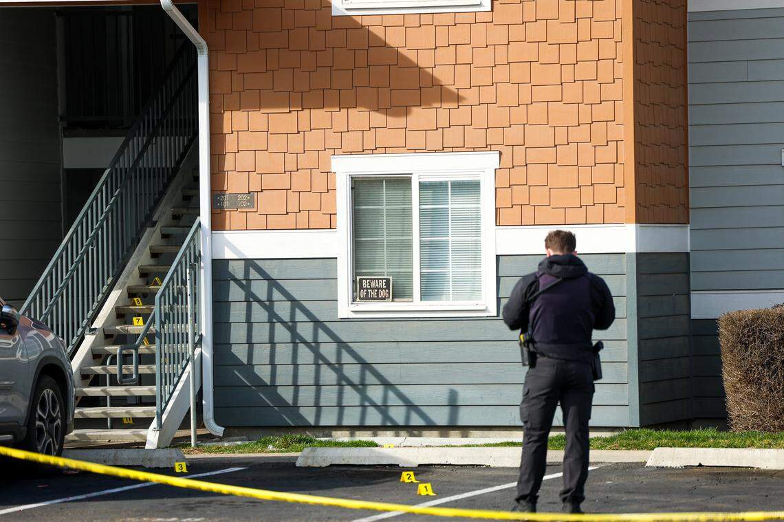 A Kennewick police officer collects evidence on the steps of the Heatherstone Apartments on Sunday afternoon.