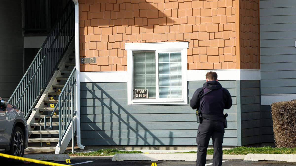 A Kennewick police officer collects evidence on the steps of the Heatherstone Apartments on Sunday afternoon.