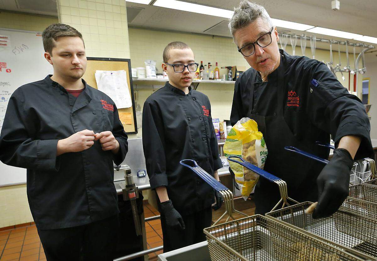 Chef Derek Smith instructs students Sawyer Johnson, left, and Tyson Tuner on using the deep fryer to cook plantains during lesson cooking a variety of items at the Opportunity Kitchen restaurant downstairs at the Federal Building in Richland. The 12-week program is operated by Columbia Ability Alliance.