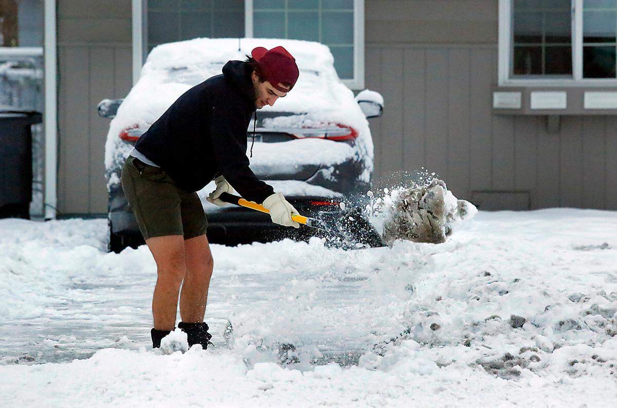 Bare legged but wearing warms boots, Giovanni Midila shovels the overnight snowfall from his driveway and from his sidewalk in front of his house in the 5100 block of West Fourth Avenue in Kennewick. Midila, a Hanford worker off the day, said he was planning on heading to a gym for a workout after shoveling the snow