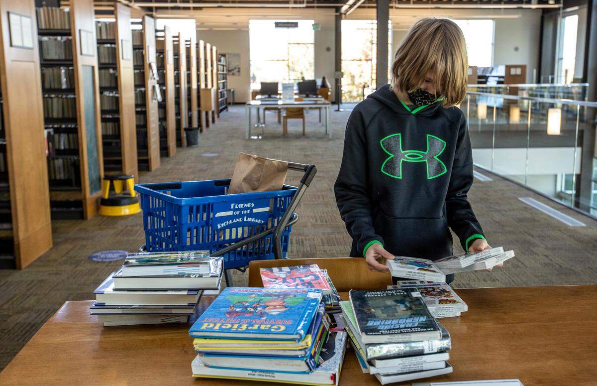 Isaac Petersen sorts through his selections from the Richland Public Library in October 2020.