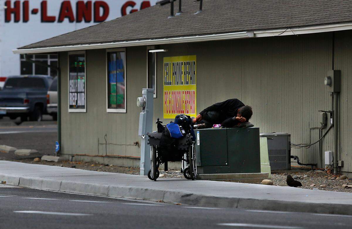 An apparent homeless man sleeps on top of an electrical transformer box in 2022 near West Clearwater Avenue in Kennewick