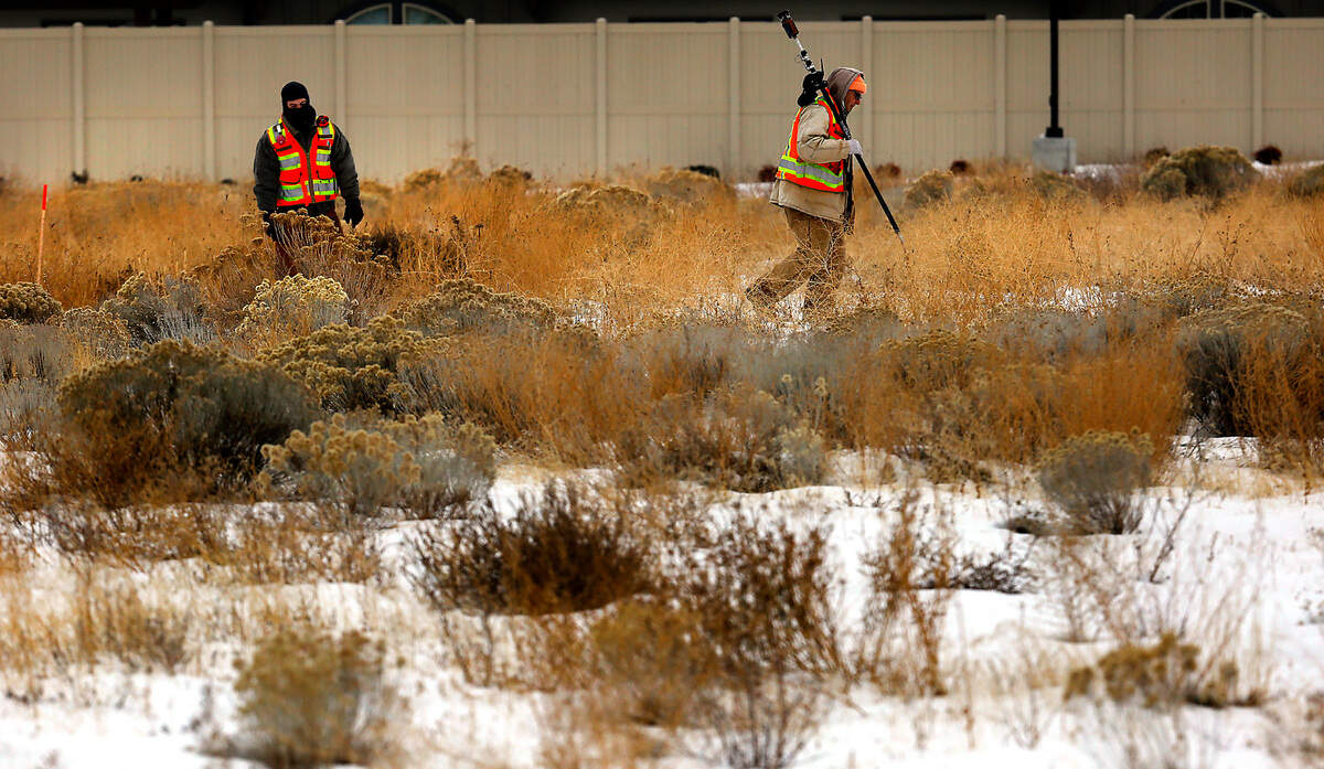 A bundled survey crew from Pasco company AHBL traipse across a snow-covered field on West 24th Avenue, marking it for a new building project. The National Weather Service forecasts the Tri-Cities could break a cold weather record as temperatures plummet to below zero this week.
