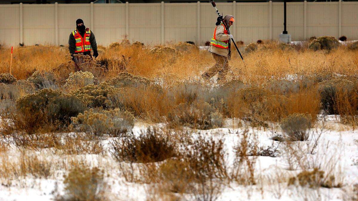 A survey crew from Pasco company AHBL traipse across a snow-covered field on West 24th Avenue, marking it for a new $22 million building project.