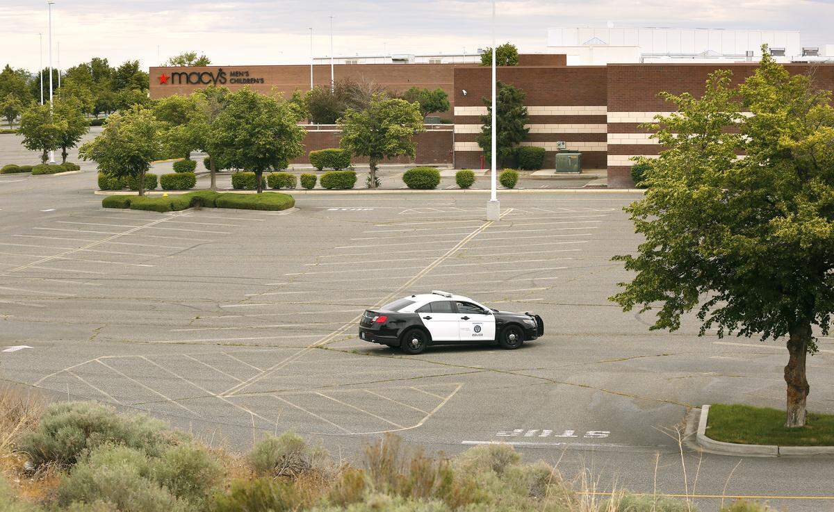 A Kennewick police car sits in the empty parking lot of Columbia Center mall in west Kennewick following Sunday night’s protests turned destructive in a nearby retail area.