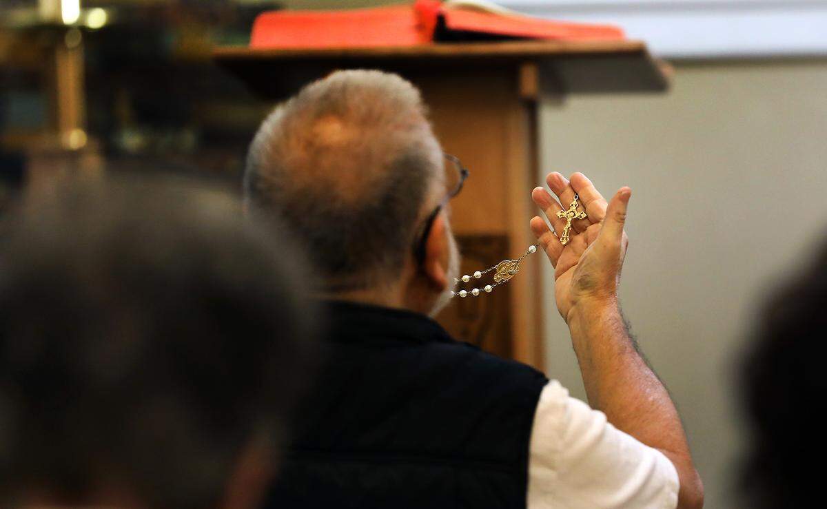 Parishioner Paul Moreno holds up a set of rosary beads before the start of a recent morning Mass in the chapel of the St. Rose of Lima Catholic Church in Ephrata.