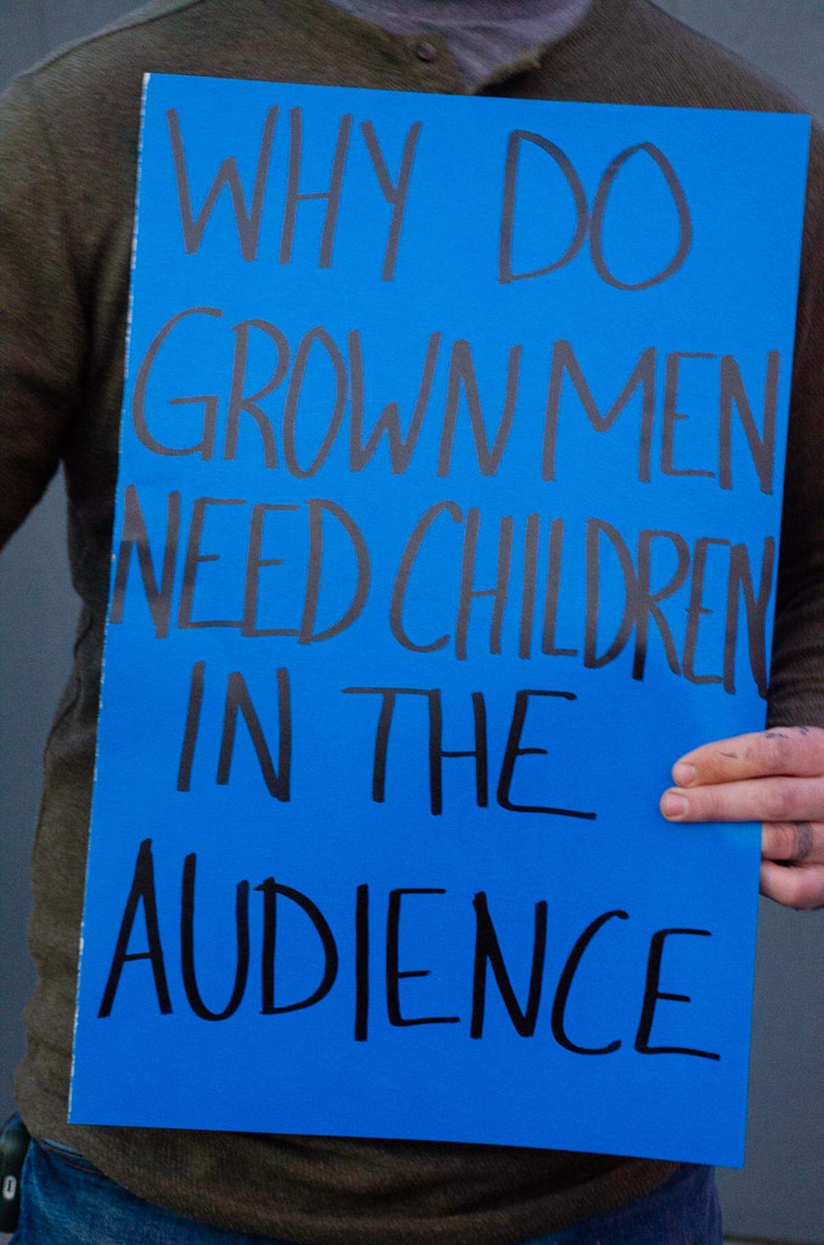 Dillon Beard, 30, of Richland, holds a sign outside Out and About nightclub in Pasco, WA during the “All Ages Disney Drag Extravaganza.” 