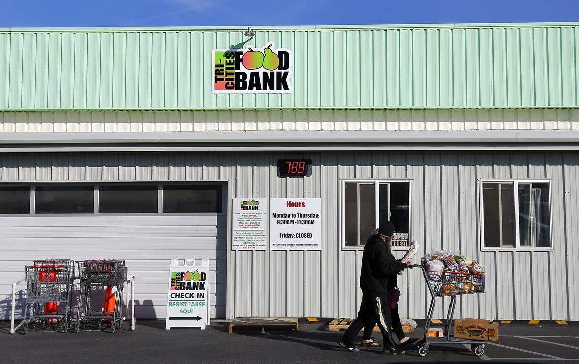 Clients leave with a grocery cart is filled with food recently at the Kennewick branch of the Tri-Cities Food Bank. Volunteers work from a list to fill carts depending on the family size and any dietary requests.