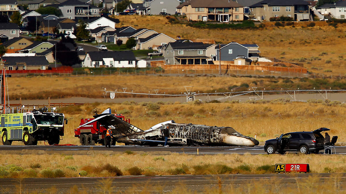 The charred remains of a privately owned small jet rests on a runway surrounded by emergency vehicles in September 2022 at the Tri-Cities Airport in Pasco.