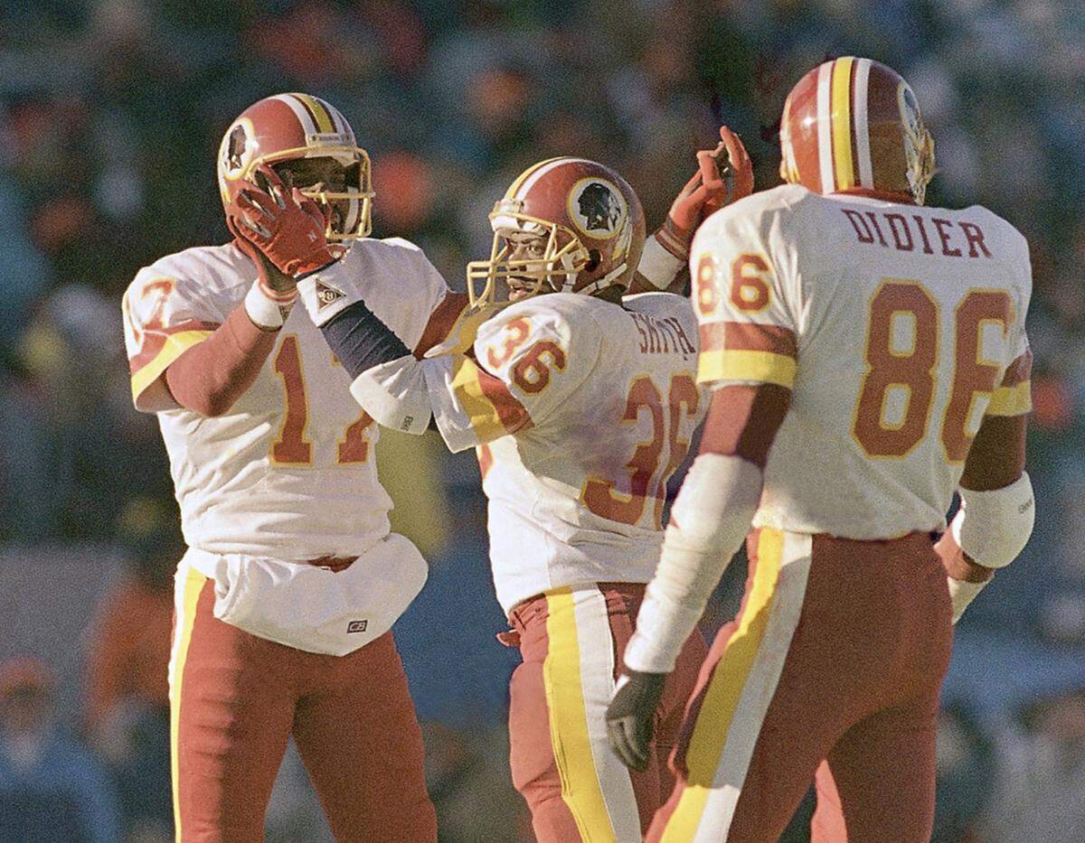 Washington Redskins Doug Williams (17), George Rogers (36) and Clint Didier (86) celebrate the Redskins’ 21-17 victory over the Bears in Chicago, Sunday, Jan. 10, 1988. (AP Photo/John Swart)