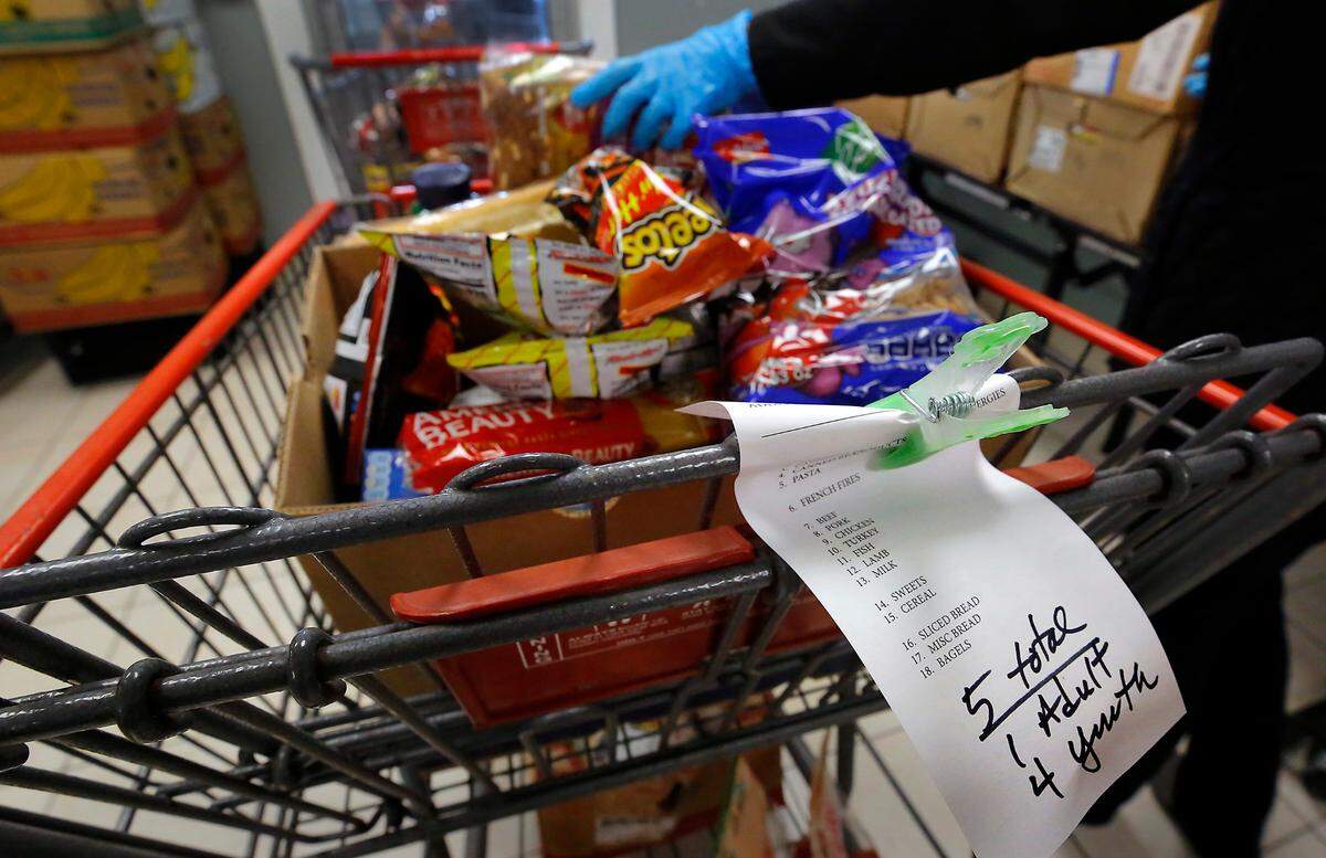 A volunteer “shopper” at the Tri-Cities Food Bank downtown Kennewick location at 420 W. Deschutes Ave. fills a cart with a variety of food items based on a list generated when the client checks in at the facility.