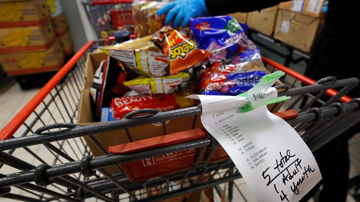 A volunteer “shopper” at the Tri-Cities Food Bank downtown Kennewick fills a cart with a variety of food items based on a list generated when the client checks in at the facility.