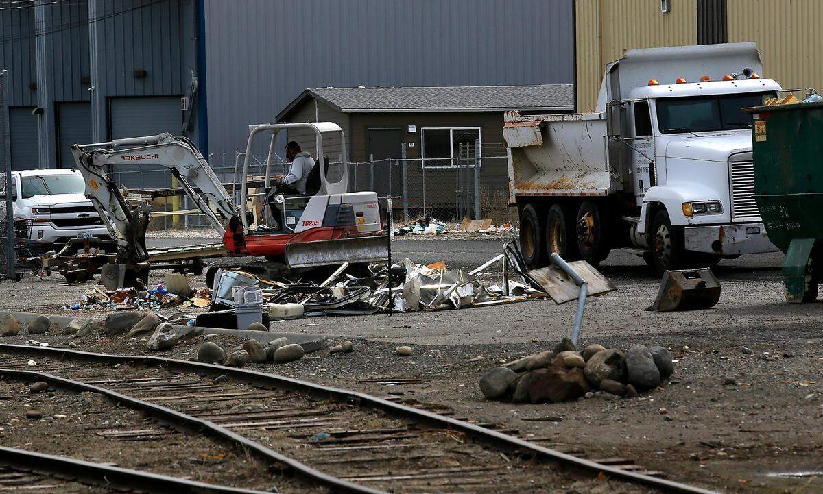 An excavator prepares to haul away pieces of abandoned recreational vehicles and trailers on Railroad Avenue in downtown Kennewick in 2023.