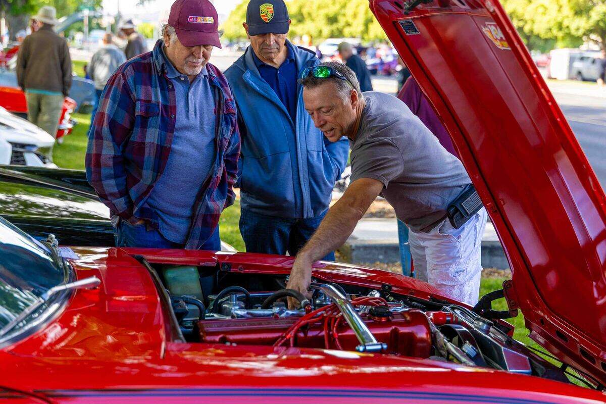 Visitors look over the engine compartment of a restored classic car Saturday during the Show N Shine at Cool Desert Nights in Richland. Car owners spent the day answering questions and sharing details about their restoration projects with spectators.