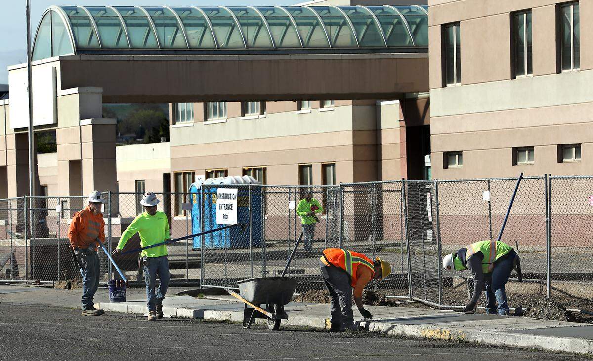 Construction crews work on the concrete sidewalks outside the former Kennewick General Hospital, the future Columbia Valley Center for Recovery.