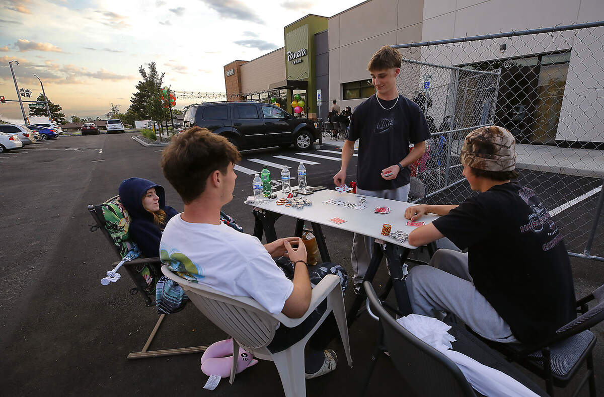 Teen friends Brooklyn Garrison, Beckett Mitchell,  Grason Mitchell and Darrius Myers, from left, play poker while waiting in line early Thursday morning for the new Panera Bread restaurant in Kennewick to open its door.