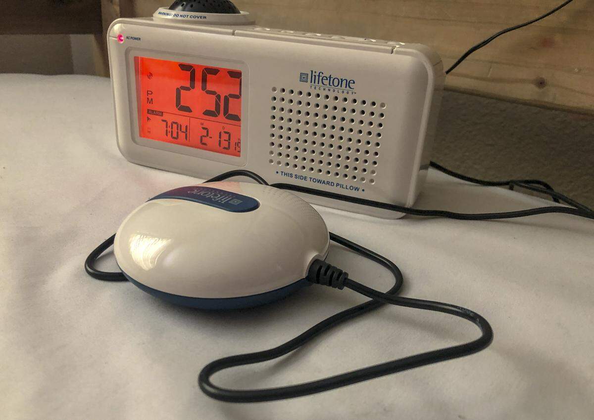 Lifetone HLAC151 Bedside Clock and Vibrating Fire Alarm uses a monitoring technology that actively listen for the high-frequency noises made from smoke alarms. Then it will vibrate, shaking the bed and waking up whoever is sleeping.