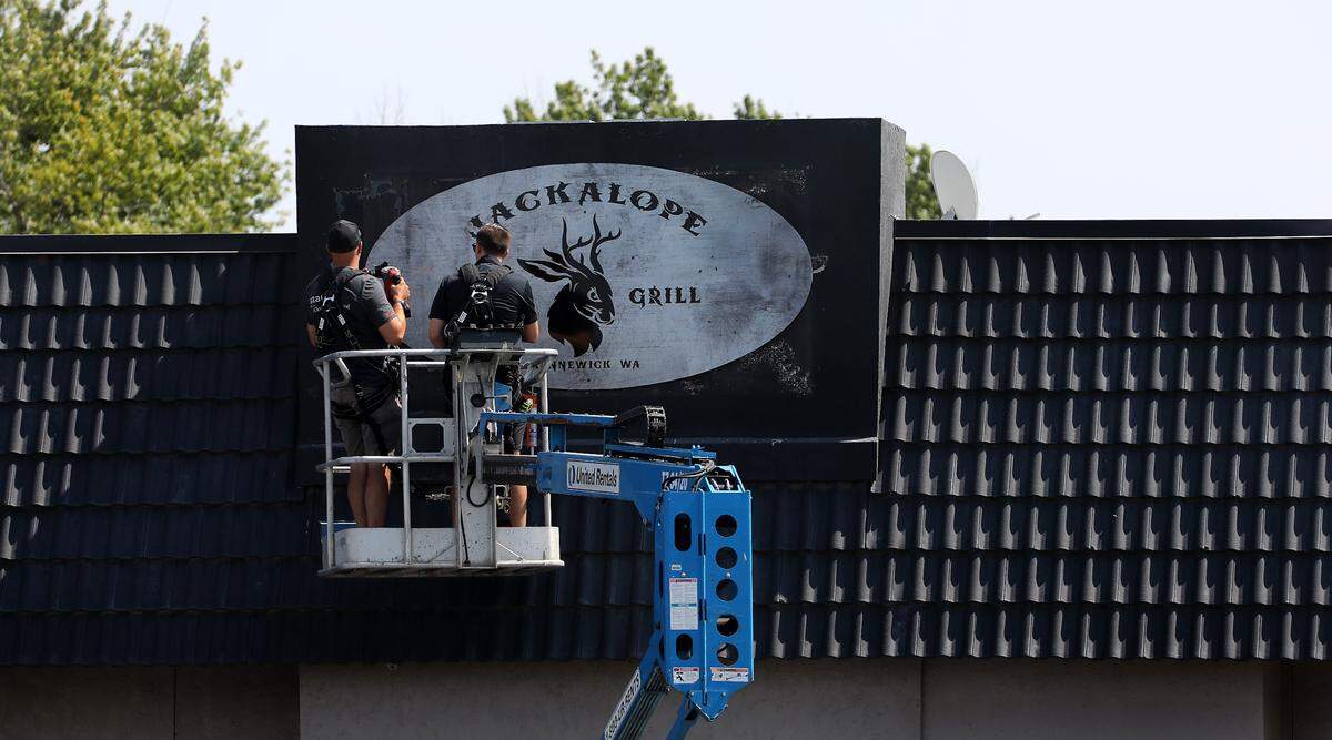 Workers in a lift attach a sign for the Jackalope Bar & Grill.