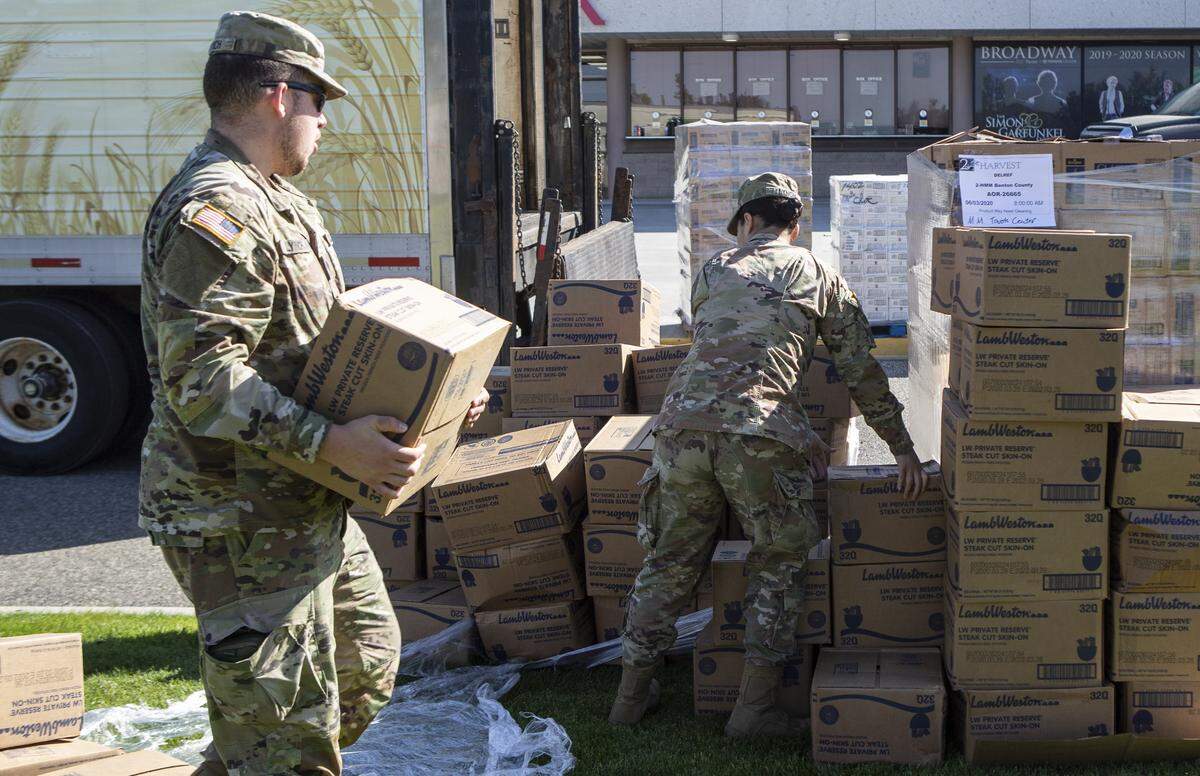 Pfc. Deanna Lynch, right, and Spc. Jarett Lynch stack a pallet of potatoes that fell apart in transit to the distribution of 700 boxes of food from Second Harvest to the Tri-Cities community on Wednesday at the Toyota Center.