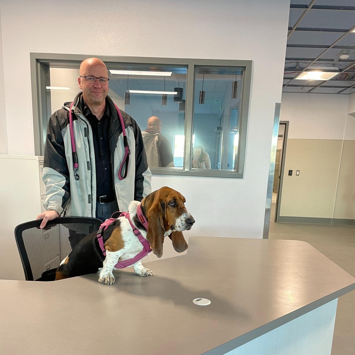 Animal Services Manager Ben Zigan and mascot DeeDee stand in the main entry of the Tri-Cities Animal Services building.